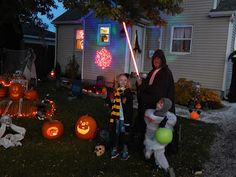 two people standing in front of a house decorated for halloween with pumpkins and lights