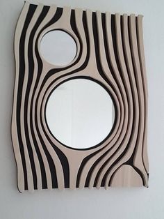 a mirror that is on the wall with black and white lines around it, as well as an oval hole in the middle