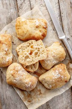 several pastries are on a piece of paper with a knife