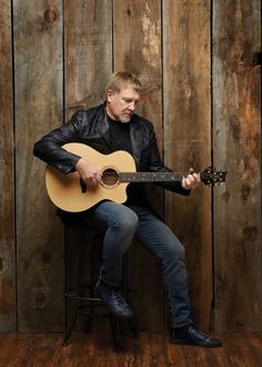 a man in black jacket playing an acoustic guitar