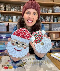 a woman holding two christmas decorations in her hands