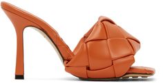 Intrecciato-woven lambskin slip-on sandals in orange. Open square toe. Logo embossed at tonal nappa footbed. Covered stiletto heel. Leather and pebble rubber sole in tan. Approx. 3.75 heel. Supplier color: Paprika Leather Open Toe Heels With Intrecciato Weave, Leather Heels With Intrecciato Weave And Open Heel, Luxury Brown Woven Leather Heels, Luxury Woven Leather Mules, Orange Leather Open Heel Mules, Designer Leather Heels With Intrecciato Weave, Luxury Heels With Woven Leather And Round Toe, Orange Leather Sandals With Padded Heel, Orange High Heel Leather Mules