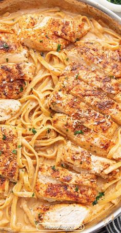 chicken and pasta in a skillet with parmesan cheese on the side, ready to be eaten