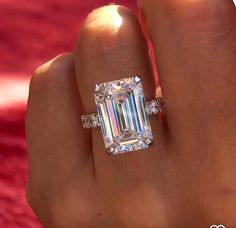 a woman's hand with a ring on it and an emerald stone in the middle