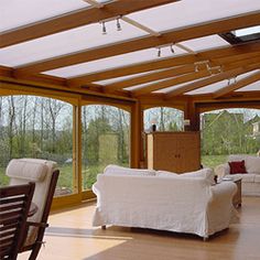 a living room filled with white furniture and lots of glass doors leading to a patio