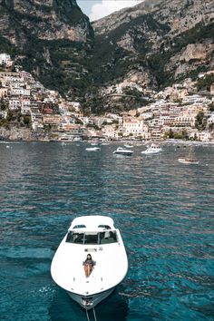 a white boat floating on top of a body of water next to a mountain range