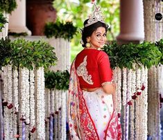 a woman in a red and white sari is posing for the camera while wearing a tiara