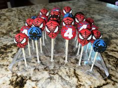 spiderman cake pops are arranged on a clear stand