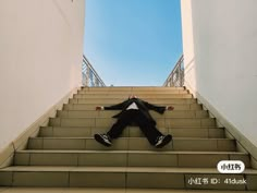 a man is laying down on the stairs with his feet in the air and arms out