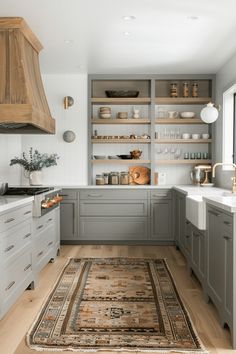 a kitchen with gray cabinets and white counter tops, an area rug in the middle