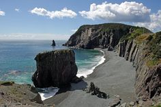 the beach is surrounded by rocky cliffs and blue water