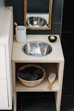 a bathroom with a sink, mirror and wooden shelf in front of black tile flooring