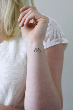 a woman with a small tattoo on her arm, showing the bike symbol in black ink