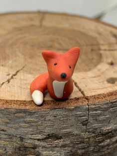 a small toy fox sitting on top of a tree stump