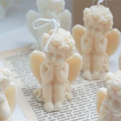 small white angel figurines sitting on top of a piece of paper next to each other