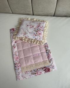 a pink and white quilted blanket laying on top of a bed next to a pillow