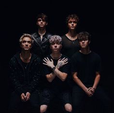 the group of young men are posing for a photo in front of a black background