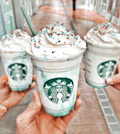 three starbucks drinks with sprinkles on them are being held by two hands