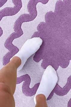 a person's feet with white socks on and purple rug in the back ground