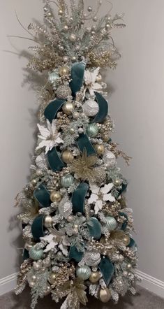 a white christmas tree with silver and green decorations