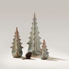 three ceramic christmas trees with a pine cone on the bottom and one in the foreground