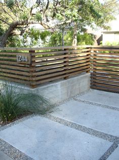 an outdoor area with wooden fence and plants on the side, surrounded by stone walkways