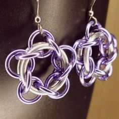 two purple and silver earrings are hanging from a mannequin's neckline