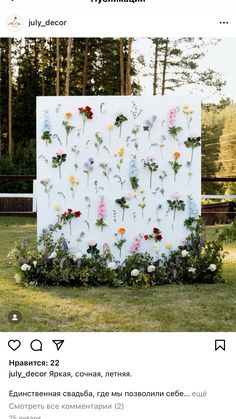 an image of flowers on a white board in the middle of grass with trees behind it