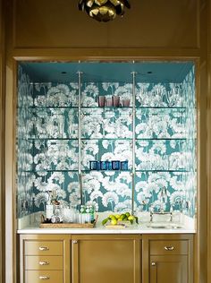 a kitchen with green wallpaper and glass shelves