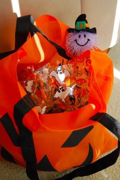 an orange bag filled with halloween candies and a stuffed animal in the top one