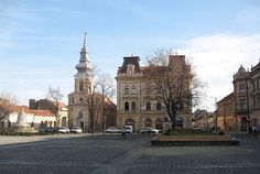 an old building with a clock tower in the background and cars parked on the street