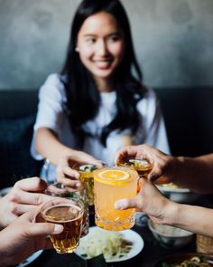 four people are toasting with drinks at a table full of food and drink glasses