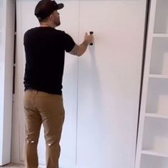 a man in black shirt and khaki pants painting a white door