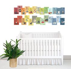 a baby's room with a white crib, potted plant and alphabets on the wall