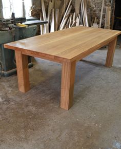 a wooden table sitting on top of a floor next to a pile of wood planks