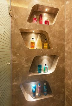 three shelves in the corner of a bathroom with soaps and lotions on them