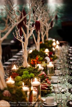 a long table with candles and moss covered trees