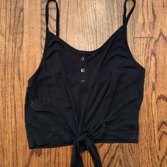 Black Tank Top With Buttons And A Tie At The Bottom. Tags On. Never Worn. Urban Outfitters Black Casual Tops, Black Tank Top For Summer Day Out, Trendy Black Tank Top For The Beach, Trendy Black Tank Top For Beach, Black Crop Top For Day Out, Urban Outfitters Sleeveless Black Crop Top, Black Cropped Tank Top For Spring, Urban Outfitters Black Casual Crop Top, Black Cotton Tank Top For Day Out