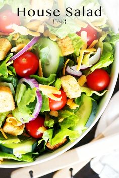 a close up of a salad with lettuce, tomatoes and croutons