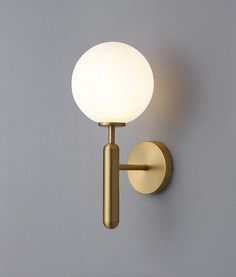 a light that is on the wall next to a gray wall with a white ball