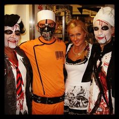 three people dressed up as zombies and one is wearing an orange shirt with white writing on it