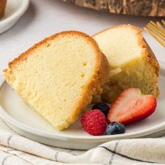 a slice of pound cake on a plate with berries and strawberries next to it