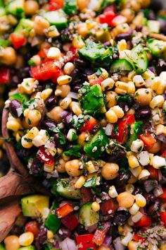 a wooden spoon filled with corn salad on top of a table