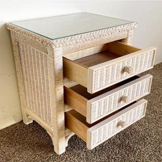 a white wicker dresser with three drawers and glass top on carpeted flooring