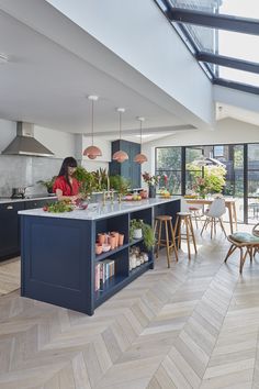 an open kitchen and dining area with blue cabinets, wood flooring and white walls