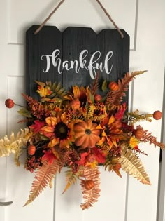 a wooden sign that says thank you with fall leaves and pumpkins hanging from the front door