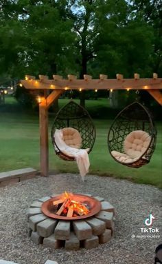 an outdoor fire pit with two hanging chairs