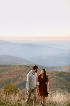 a man and woman standing on top of a hill