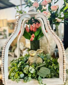 a white wooden frame with flowers and a rabbit in the center surrounded by greenery