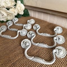 several metal handles sitting on top of a brown chair next to flowers and a vase